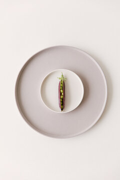 Marrow fat peas still in their skin lying on a small plate.