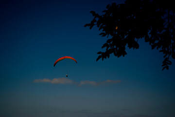 Gleitschirmflieger vor blauem Abendhimmel und weißen Wolken 