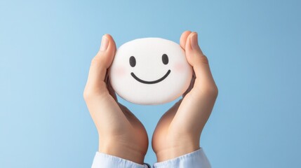 hands holding a smiley face against a blue background