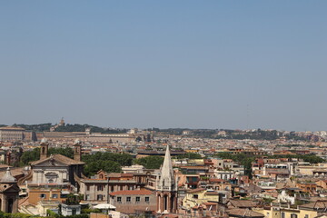 Obraz premium Panoramic view of Rome with historic buildings, churches, and Vatican City in the background under a clear blue sky