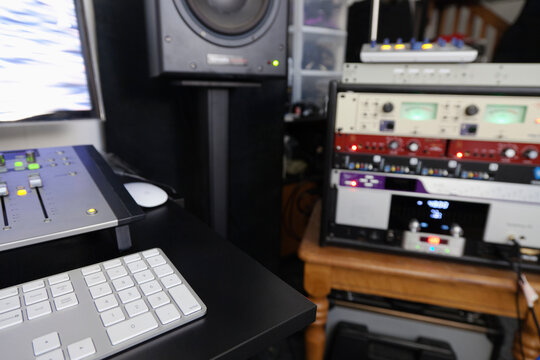A computer workstation with sound board, speakers, headphones, recording deck and amplifier in a home recording studio