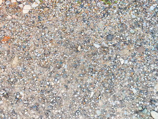 Texture of gravel surface with mixed stones and sandy patches in a natural outdoor setting, ideal for overlaying text or graphics