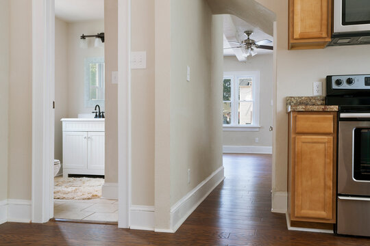 Interior view of a bathroom, kitchen and hallway with neutral decor and colour scheme.