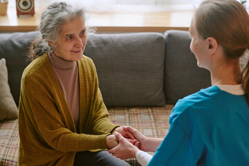 Obraz premium High angle shot of senior woman looking at nurse with smile while she holding her hands