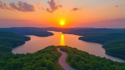 Sunset over a winding road and lake.
