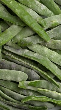 Top view of frozen whole young cranberry bean pods background.  Table spin. Vertical video.