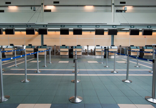 An airport check in area, closed desks and empty wait line queuing spaces.