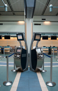 An airport check in area, closed desk and self check in terminals.