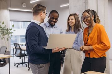 Smiling diverse professionals collaborating, sharing laughter during team project at modern office, embodying workplace camaraderie and inclusivity