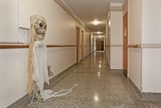 A long corridor in a building, a ghost costume hanging from a wall hook.