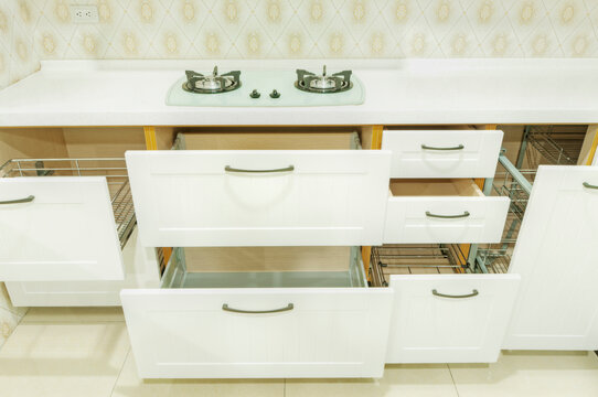 A newly installed modern kitchen with cabinets, two sinks, gas stove, fitted cupboards with red cupboard doors.