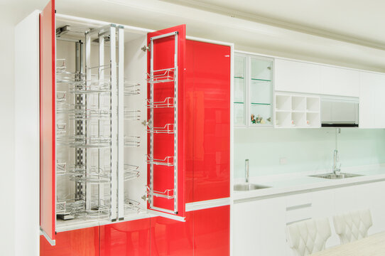 A newly installed modern kitchen with cabinets, two sinks, gas stove, fitted cupboards with red cupboard doors.