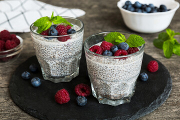 Healthy breakfast or morning with chia seeds vanilla pudding raspberry and blueberry berries on table background, vegetarian food, diet and health concept. Chia pudding with raspberry and blueberry