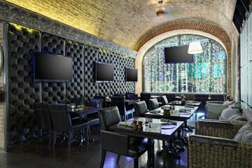 Restaurant interior with TV screens on leather covered wall.