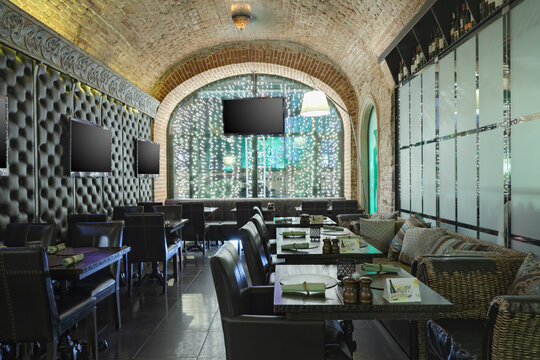 Restaurant interior with one wall made of glass and other of leather.