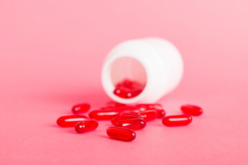 Red pills spilled around a pill bottle. Medicines and prescription pills flat lay background. Red...