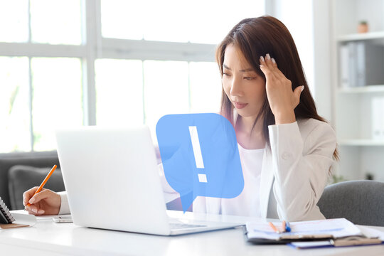 Tired Asian businesswoman working at table in office - Powered by Adobe