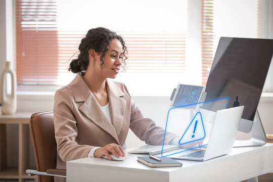 Young African-American QA engineer working with laptop and computer in office