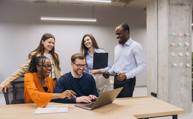 Professional team collaborating, discussing project details, working together on laptop in modern, bright office setting