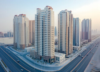 Fototapeta premium Modern urban landscape showcasing towering residential buildings along a busy highway during a soft light sunset creating a serene ambiance