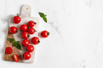 Board with fresh cherry tomatoes and basil on white background