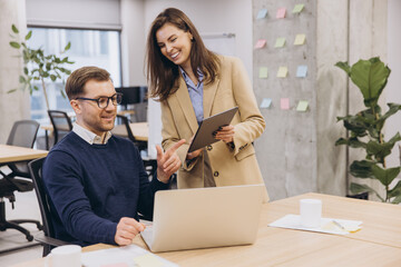 Business colleagues working together, analyzing data on laptop and tablet in modern workspace