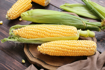 Fresh corn cobs on dark wooden table, closeup