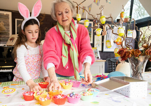 Grandmother and granddaughter laying  the table for an Easter celebration meal. 