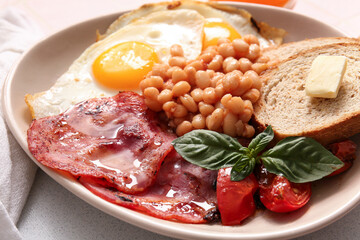 Plate of tasty English breakfast with fried eggs on table