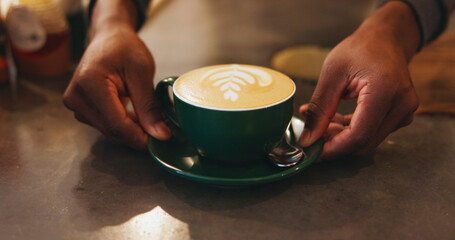 Hands, latte art and presentation with barista at coffee shop counter for hospitality or service closeup. Creative, cup and drink with care or restaurant employee in startup cafe for small business