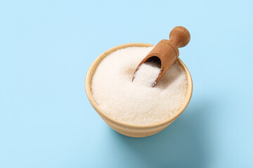 Bowl with white sugar on blue background