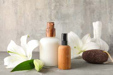 Bottles of cosmetic products, spa accessories and lily flowers on grunge background