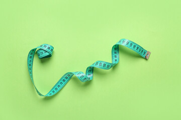 Turquoise measuring tape on green background