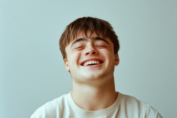 Fototapeta premium A young man with short brown hair is smiling and looking at the camera. He is wearing a white shirt and he is happy