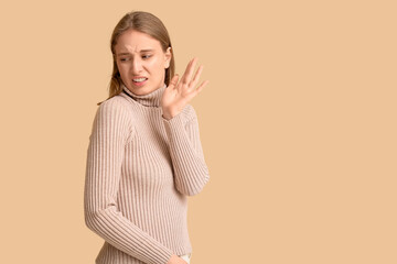 Young woman feeling bad smell on beige background