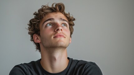Obraz premium Contemplative young man looking up indoor setting portrait photography soft lighting reflective mood