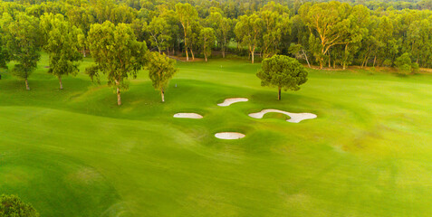 An aerial view of a golf course with sand traps surrounded by vibrant greenery.