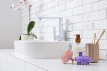 Hair scalp massagers on chest of drawers near sink in bathroom