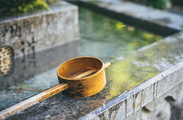 Isolated traditional japanese bamboo wooden laddle. Purification water fountain chozubachi.