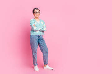 Smiling older woman with trendy casual outfit posing in front of pastel pink background exuding positivity and spring vibrancy