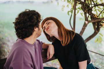 Obraz premium A cheerful couple sits on a bench in a garden, playfully making funny faces at each other, creating a joyful and lighthearted moment.