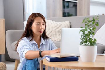 Young Asian businesswoman working with laptop on table at home