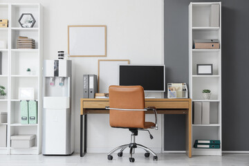 Interior of office with workplace, shelf units and water cooler