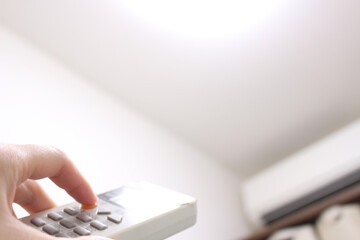 エアコンのリモコンを操作する手