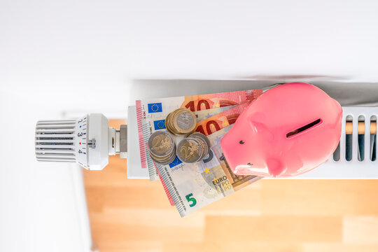 Paris, France - 02 07 2025: A piggy bank, banknotes and stacks of euro coins are placed on a radiator..