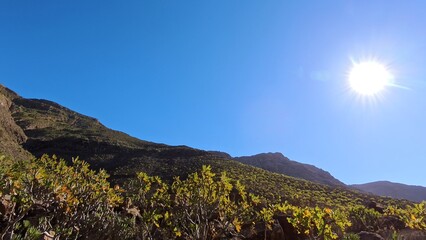 schroffe Berggipfel unter blauem Himmel, Sonne, idyllische Berge, Berghang, Lanzarote, Kanaren, Wandern, Flora, Natur, einsam, ruhig, Pfad, steinig, hügelig, Landschaft
