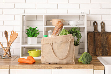 Shopping bag with different fresh products on counter in kitchen