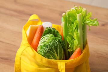 Shopping bag with different fresh products on wooden table, closeup