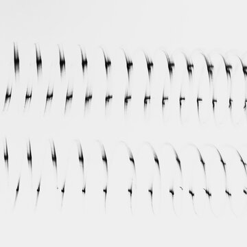 Abstract pattern, length of fine wire wound around and stretched, black and white image, marks against a plain pale background,