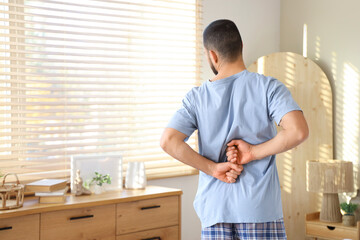 Young man in pajamas suffering from back pain at home